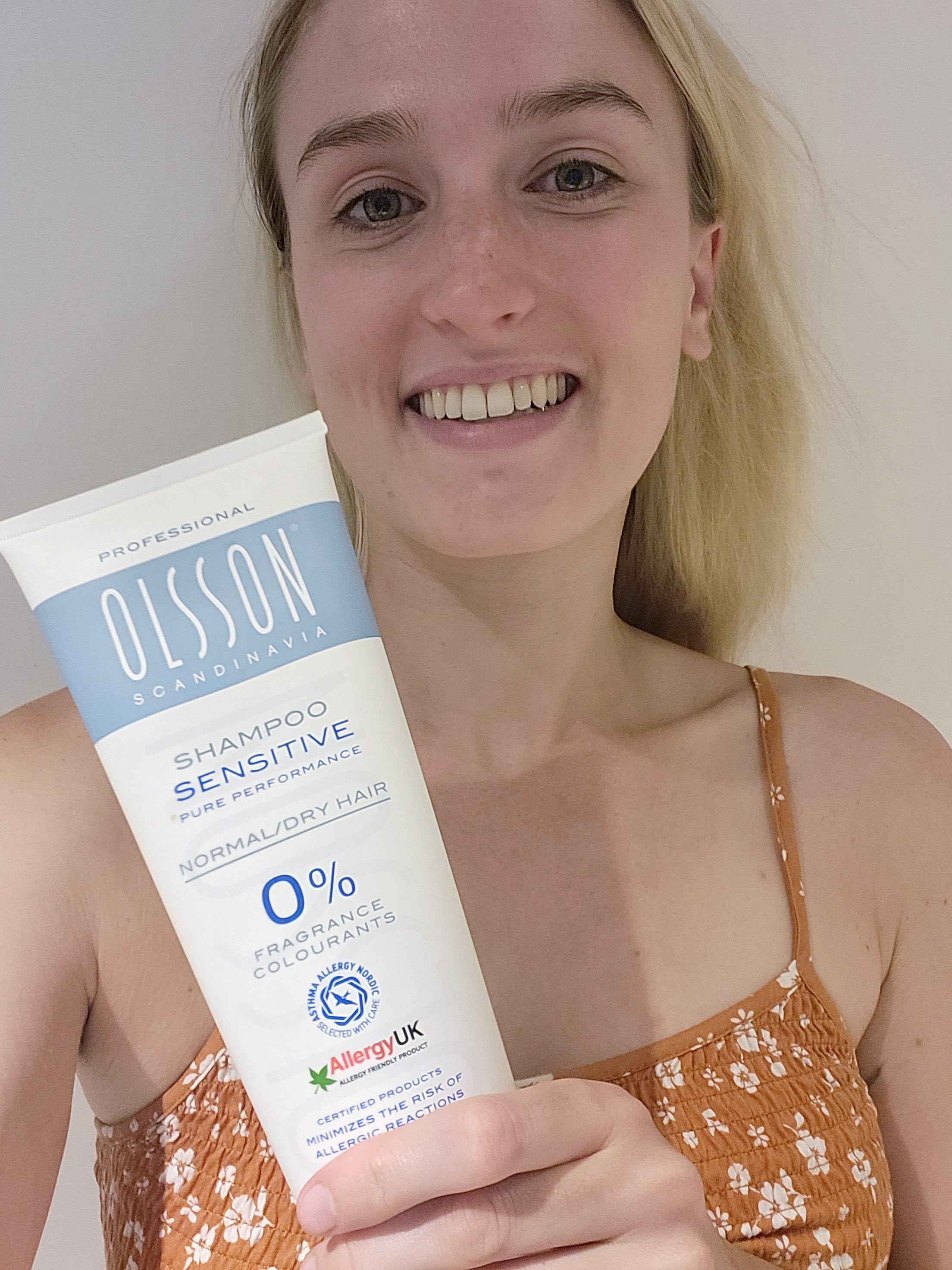 Imogen Tingay (Olsson Product Reviewer). Holds a bottle of Olsson Scandinavia shampoo smiling. 